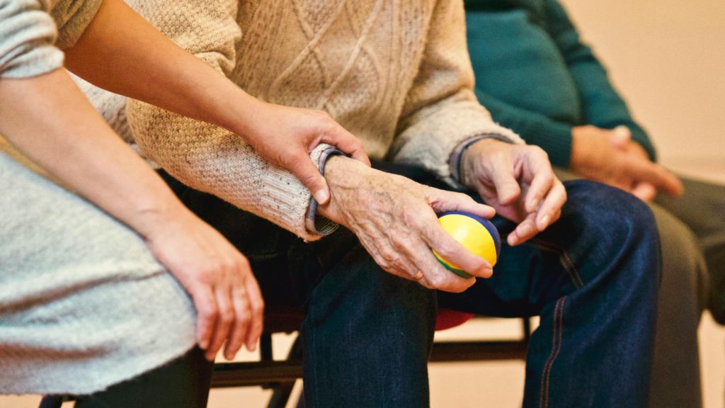 pexels photo 339620 339620 An elderly person receives support from a caregiver, holding hands indoors, showcasing compassion.